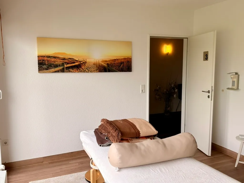 Behandlungsliege mit Blick zur Tür und ruhigem Wandbild